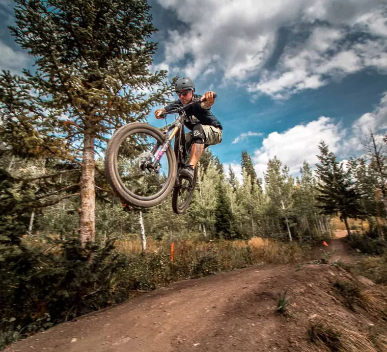 A mountain biker in the air off a trail jump
