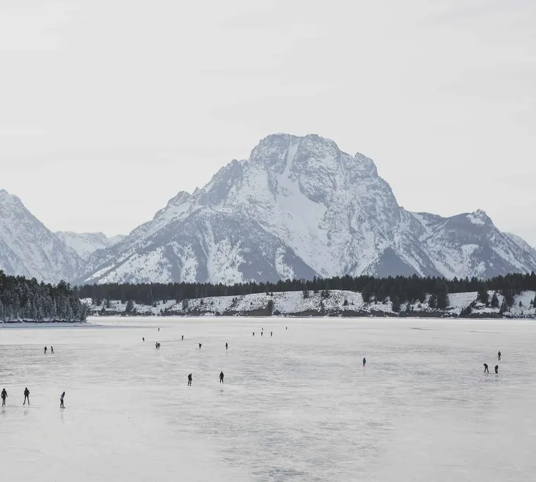 Mount Moran above a frozen lake with skaters