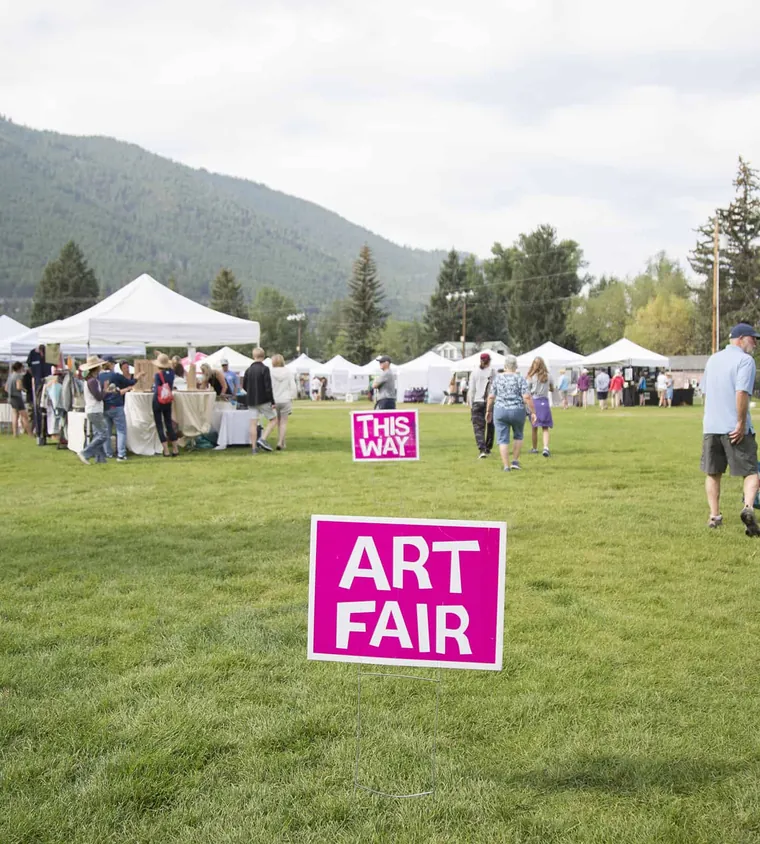 “ART FAIR” sign and white tents on a park lawn