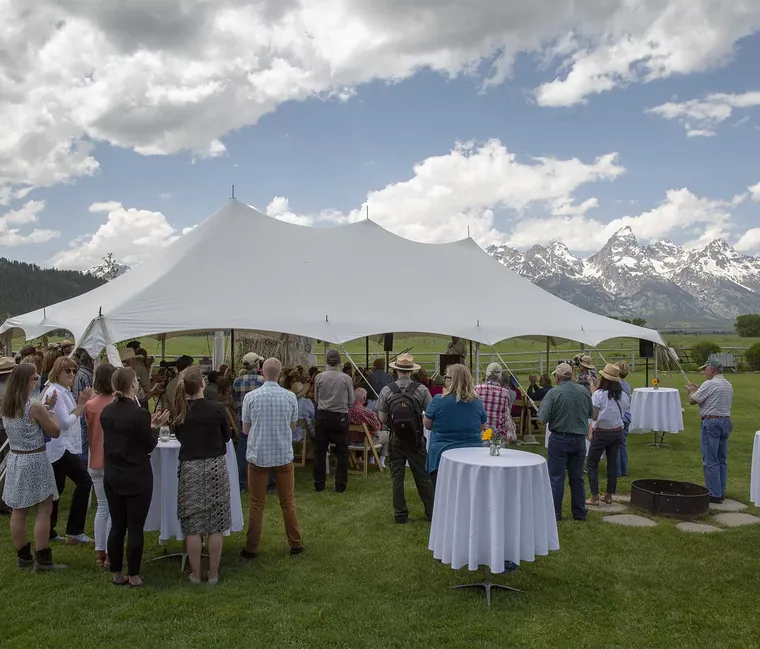 Guests at an outdoor tented reception with the Tetons behind